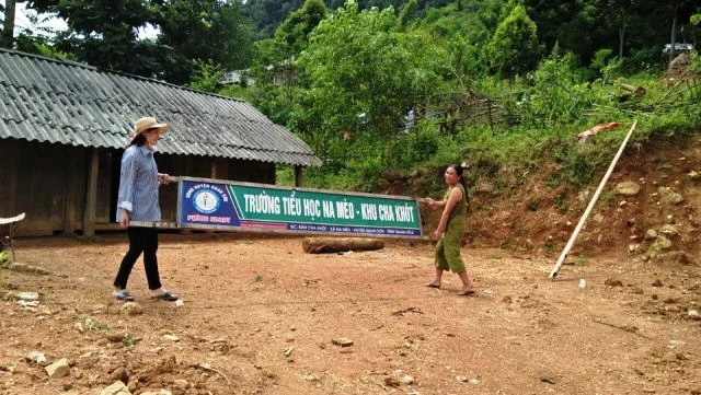 Cô giáo Vi Thị Chuyên và phụ huynh khiêng tấm biển của điểm trường do bị mưa lũ làm rơi.