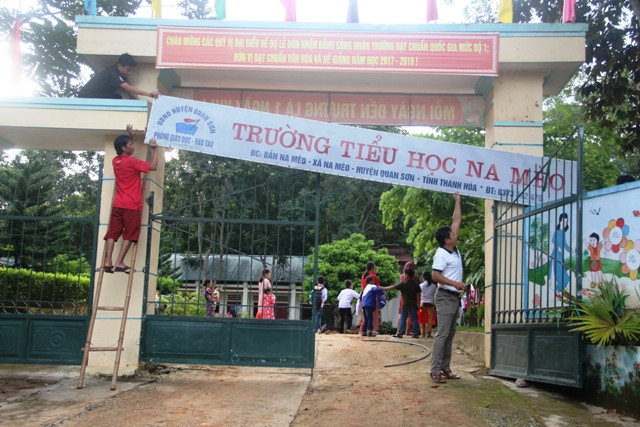 Các thầy giáo chỉnh trang lại tấm biển tên trường.