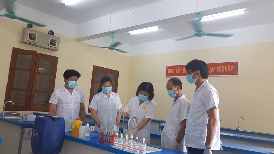 Cô Mai Thị Thao (giữa) hướng dẫn nhóm giáo viên pha chế dung dịch sát khuẩn tay khô. Ảnh: NVCC.