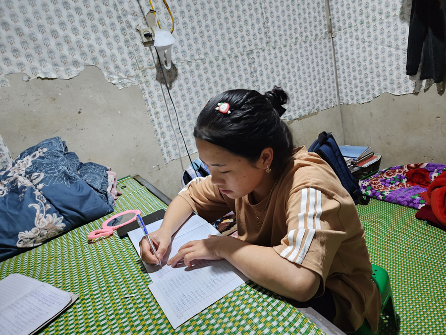 Phòng trọ chật hẹp, Xồng Y Ồng (HS Trường THPT Kỳ Sơn, Nghệ An) dùng giường làm bàn học để làm bài tập về nhà buổi tối. Ảnh: Hồ Lài.