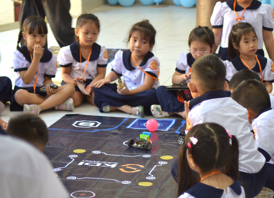 Các em học sinh thích thú với hoạt động điều khiển robot. Ảnh: H.P.