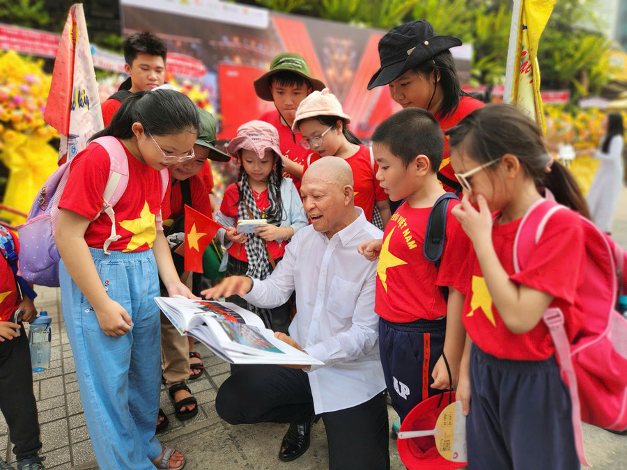 Nhiếp ảnh gia Nguyễn Á trò chuyện cùng các em học sinh tham quan triển lãm. Ảnh: L.N.