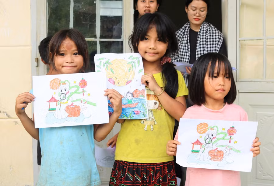 Các bé gái vùng cao hào hứng khoe tranh vẽ cùng các tình nguyện viên. Ảnh: DOP