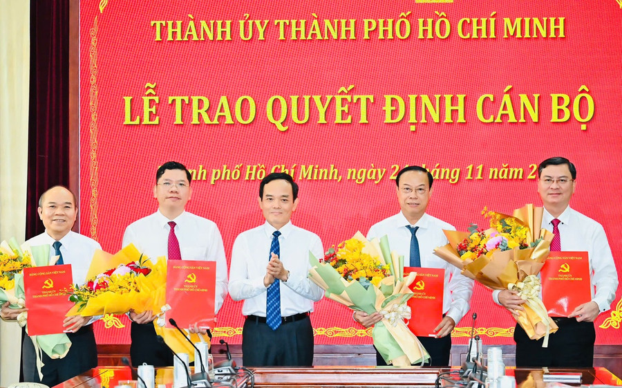 Ông Trần Lưu Quang, Bí thư Thành ủy TPHCM (giữa) trao quyết định và tặng hoa chúc mừng các tân lãnh đạo HĐND và UBND TPHCM. Ảnh: SGGP