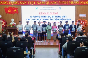 Đại diện Ban giám hiệu Trường Đại học Ngoại ngữ, Đại học Đà Nẵng tặng quà lưu niệm cho lưu học sinh Lào trong lễ khai giảng. 