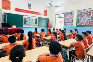 Các em học sinh lớp 3A1, trường Tiểu học Cao Xá (huyện Lâm Thao) xem video, tư liệu tìm hiểu về thân thế, sự nghiệp của Bác Hồ kính yêu.