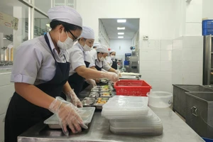 Nhân viên Trường THPT Trung Vương phân chia khẩu phần thức ăn ra từng khay.