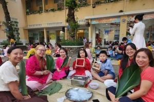 Học sinh, giáo viên và phụ huynh Trường Tiểu học Trần Hưng Đạo cùng nhau gói những chiếc bánh chưng xanh trong ngày hội "Gói Tết-Trao Xuân".