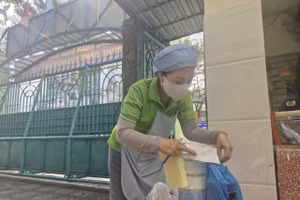 Bảo mẫu Trường Tiểu học Tân Quy (phường Tân Hưng) nhận đồ ăn phụ huynh mang đến cho con trưa 29/1.