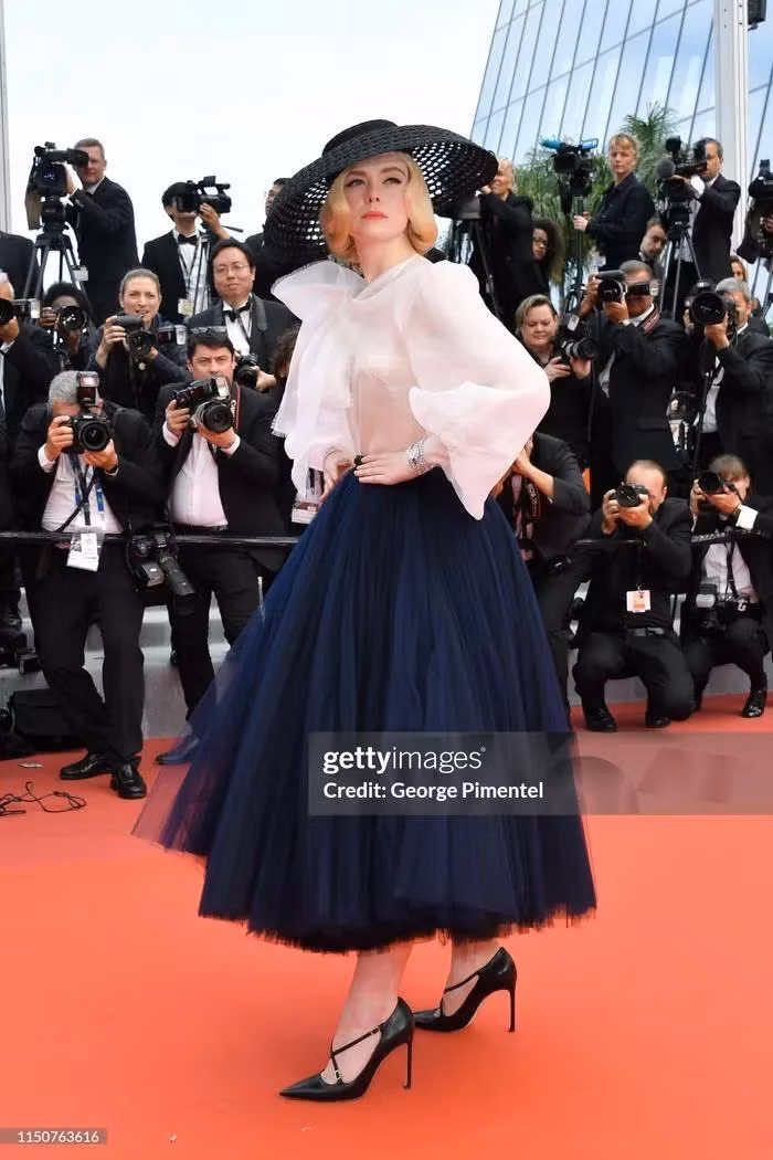 Elle Fanning hóa thân thành một công nương với chiếc váy xòe rộng, áo sơ mi bồng bềnh cách điệu cùng nón rộng vành. Hoa hậu đẹp nhất thế giới xuất hiện lộng lẫy tại Cannes 2024