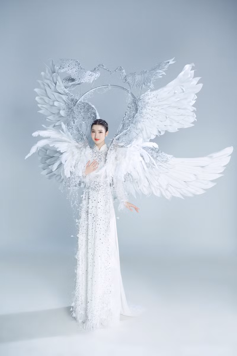 Bộ trang phục mang tên 'Cò ơi' với trung tâm là áo dài truyền thống, đằng sau là hai chiếc cánh lớn và khung tròn có 2 chú cò hướng mặt vào nhau. Các chi tiết được đính kết thêm kim tuyến, đá và dây ngọc giúp trang phục thêm lấp lánh. Cận cảnh trang phục dân tộc hơn 10kg của Phương Nhi tại Miss International 2023