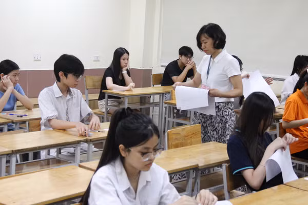 Giám thị phát giấy thi cho thí sinh.