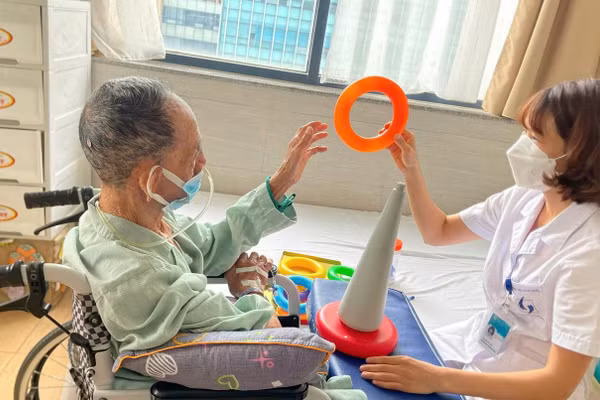 Chị Nguyễn Thị Cúc - cựu sinh viên Trường Đại học Kỹ thuật Y tế Hải Dương can thiệp hoạt động trị liệu cho người bệnh tại Bệnh viện Lão khoa Trung ương.