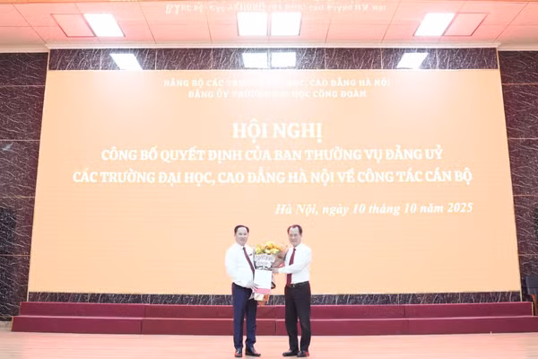 Đồng chí Nguyễn Thanh Sơn - Bí thư Đảng ủy các trường Đại học, Cao đẳng Hà Nội (bên phải) trao quyết định và tặng hoa cho đồng chí Lê Mạnh Hùng.