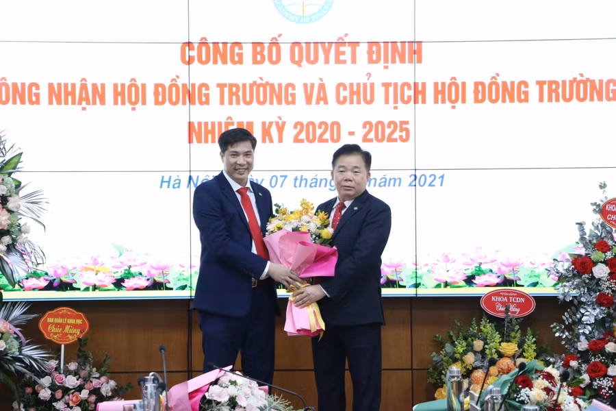 PGS.TS. NGND Nguyễn Trọng Cơ - Giám đốc Học viện Tài chính (bìa phải) tặng hoa tân Chủ tịch Hội đồng trường Nguyễn Đào Tùng. Ảnh: Nhật Nguyên.