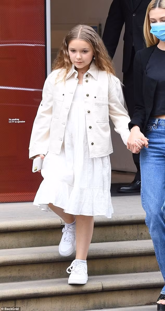 Cô bé diện nguyên cây trắng, với váy baby-doll, áo khoác và giày thể thao.