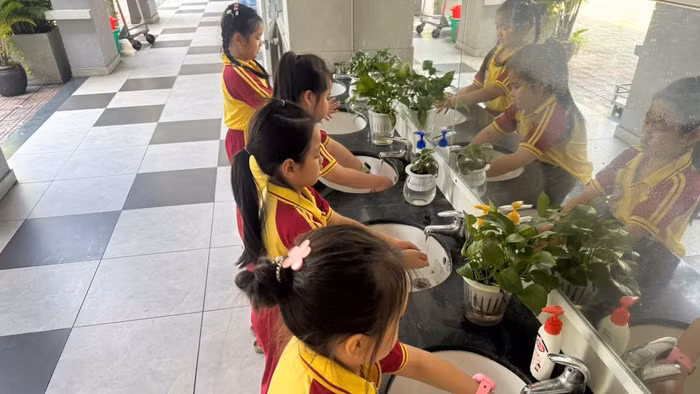 Học sinh Trường Tiểu học Hồ Văn Huê (phường Đức Nhuận, TPHCM) rửa tay sau khi tham gia hoạt động ngoài trời.