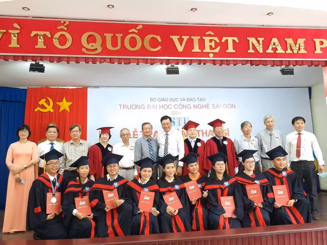 Các tân thạc sĩ chụp hình lưu niệm cùng với các đại biểu và ban giám hiệu nhà trường