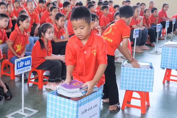 Học sinh Trường Tiểu học Nghi Văn (xã Nghi Văn, Nghệ An) quyên góp sách tặng cho bạn học khó khăn và tủ sách dùng chung. Ảnh: Hồ Lài