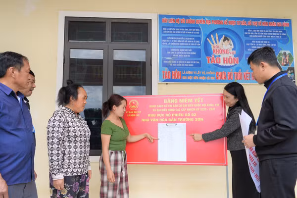 Cán bộ xã Nậm Cắn (Nghệ An) hướng dẫn người dân bản Trường Sơn đọc thông tin danh sách cử tri ở điểm bầu cử. Ảnh: Hồ Lài