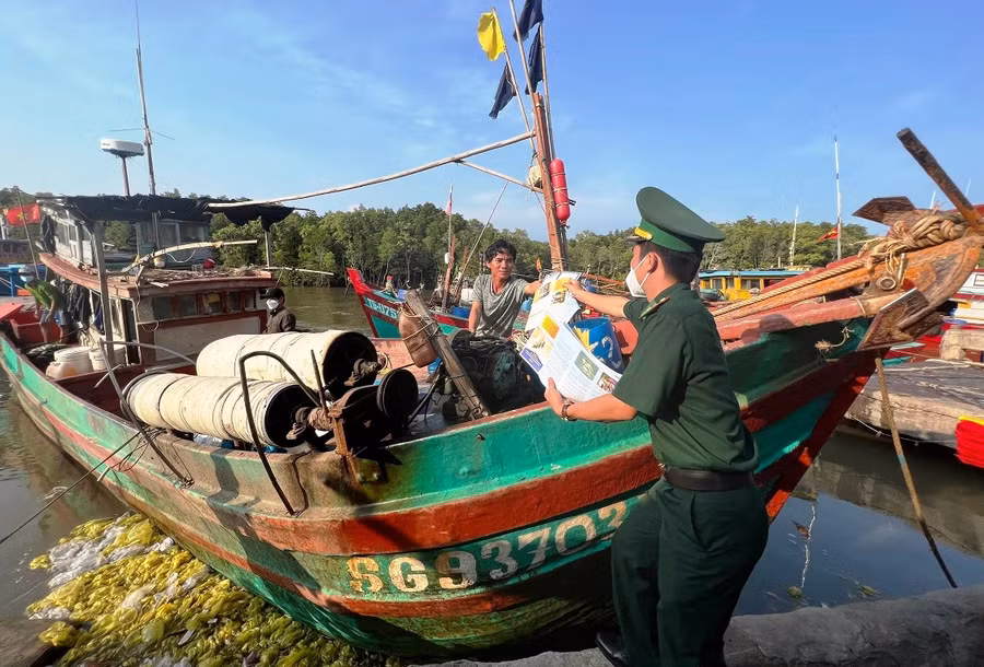 Đoàn viên lực lượng Biên phòng TPHCM phát tờ rơi tuyên truyền các quy định của pháp luật cho bà con ngư dân.