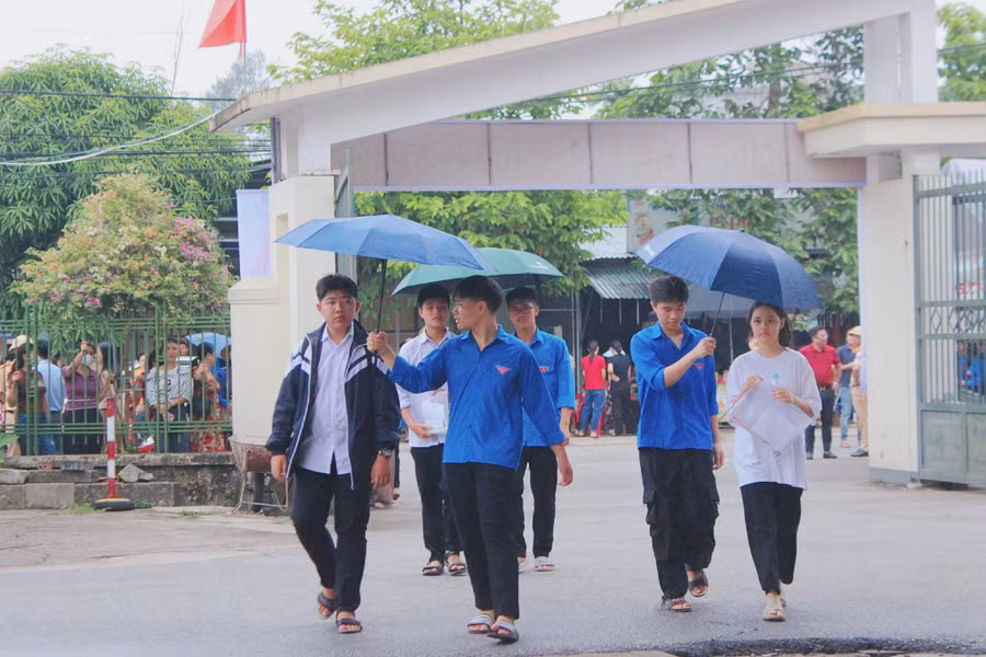 Tình nguyện viên che ô tránh mưa cho thí sinh vào phòng thi. Tình nguyện viên che ô tránh mưa cho thí sinh vào phòng thi.