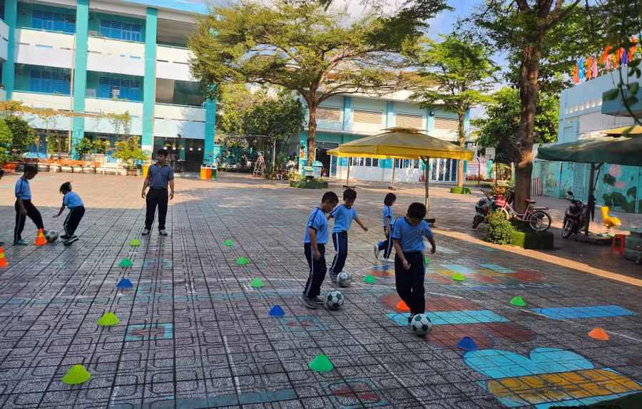 Giờ học thể dục của học sinh Trường tiểu học Lê Văn Thọ được tổ chức vào buổi sáng, dưới bóng cây và có bố trí quạt xung quanh.