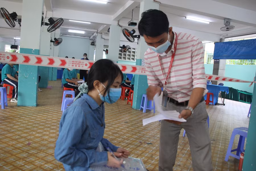 Cán bộ tại điểm tiêm hướng dẫn học sinh khai báo y tế.