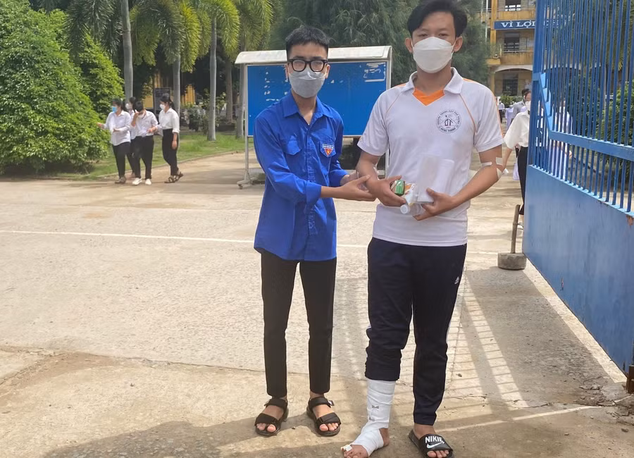 Thanh niên tình nguyện hỗ trợ thí sinh đến điểm thi THPT Đông Thạnh.