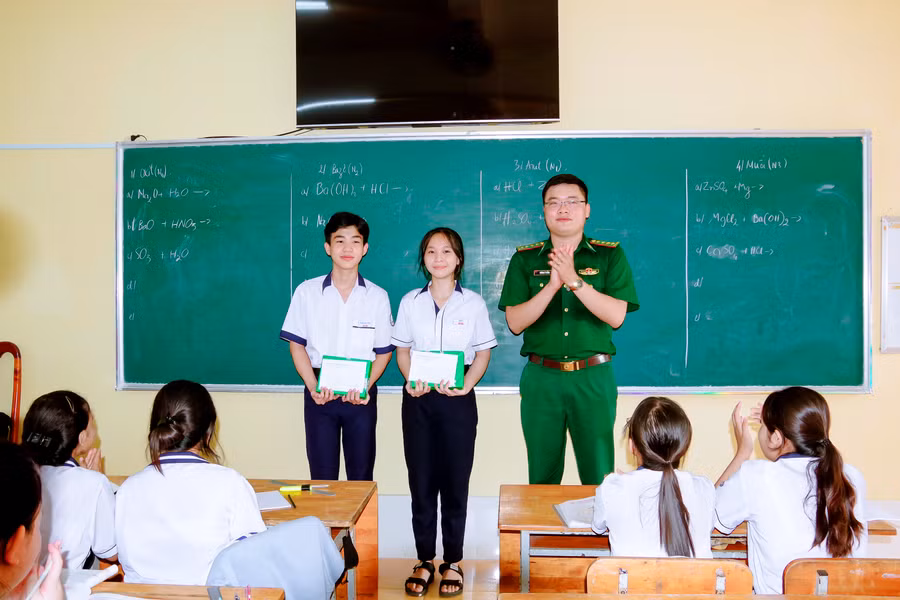 Đại úy Huỳnh Lý Tưởng, Chính trị viên đồn Biên phòng Trung Bình trao học bổng cho các em học sinh trong chương trình “Nâng bước em tới trường”.
