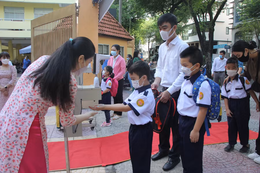 Học sinh đo thân nhiệt và rửa tay trước khi vào dự tựu trường.