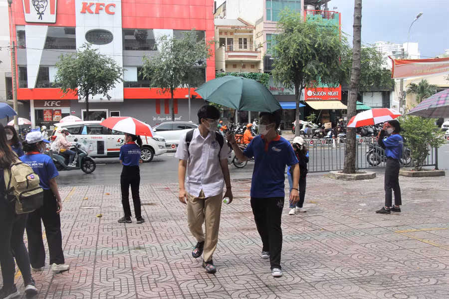 Các bạn tình nguyện viên dùng ô che nắng cho thí sinh vào điểm thi.