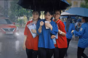 Tình nguyện viên hỗ trợ thí sinh rời điểm thi khi mưa lớn.
