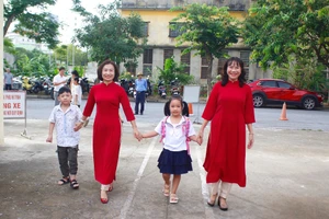 Cô giáo ân cần dắt tay học sinh lớp 1 trong ngày đầu tiên tới trường.