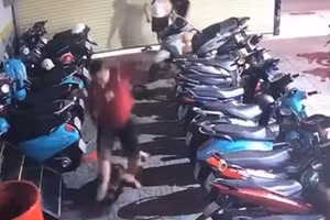 Chủ tiệm Internet (áo thun đỏ) dùng chân đạp vào mặt thiếu niên. (Ảnh: Cắt từ video trên mạng xã hội)