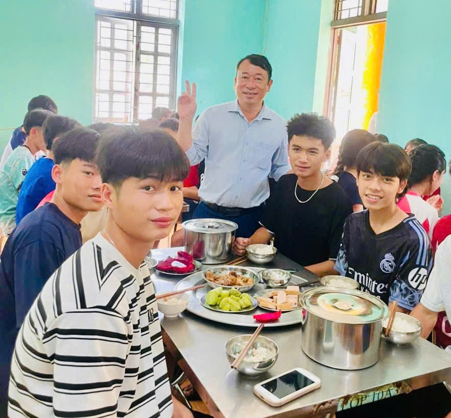 Ông Cà Văn Minh - Hiệu trưởng Trường PTDTNT THPT Mường Ảng (đứng giữa) động viên học sinh trong bữa cơm tập thể.