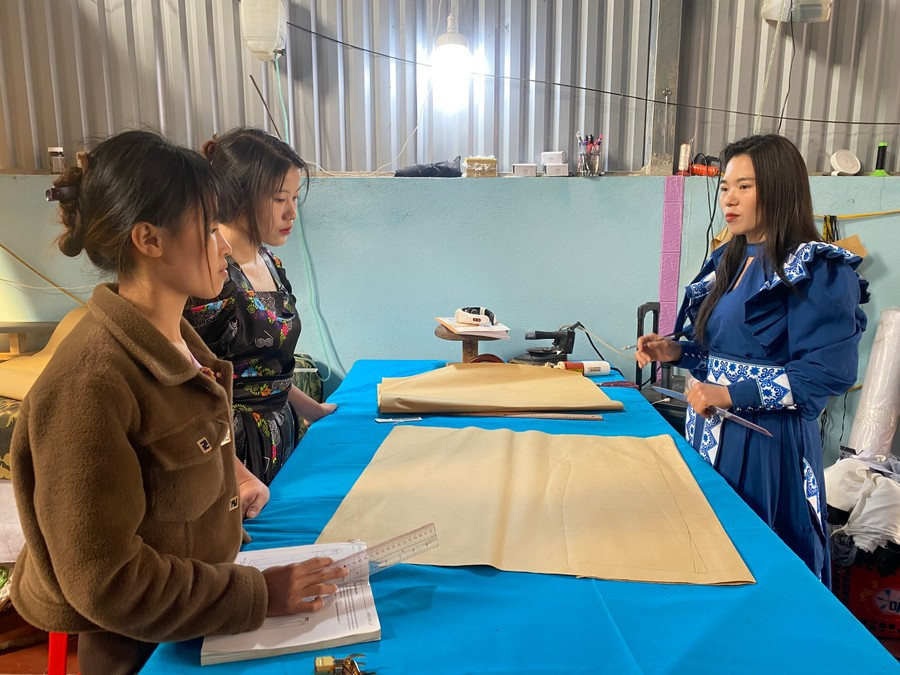 Chị Giàng Thị Mỷ (bên phải) hướng dẫn các học viên học nghề may.