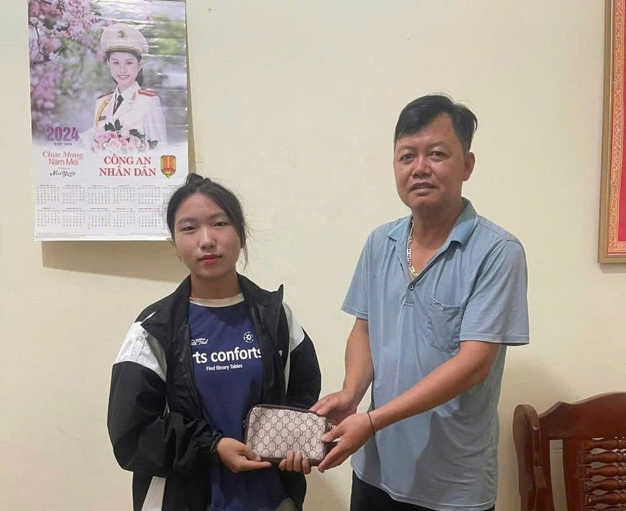 Thầy Phạm Ngọc Nguyễn (bên phải) trao trả lại ví kèm tài sản, giấy tờ tùy thân cho người đánh rơi tại trụ sở Công an xã Mường Nhé.