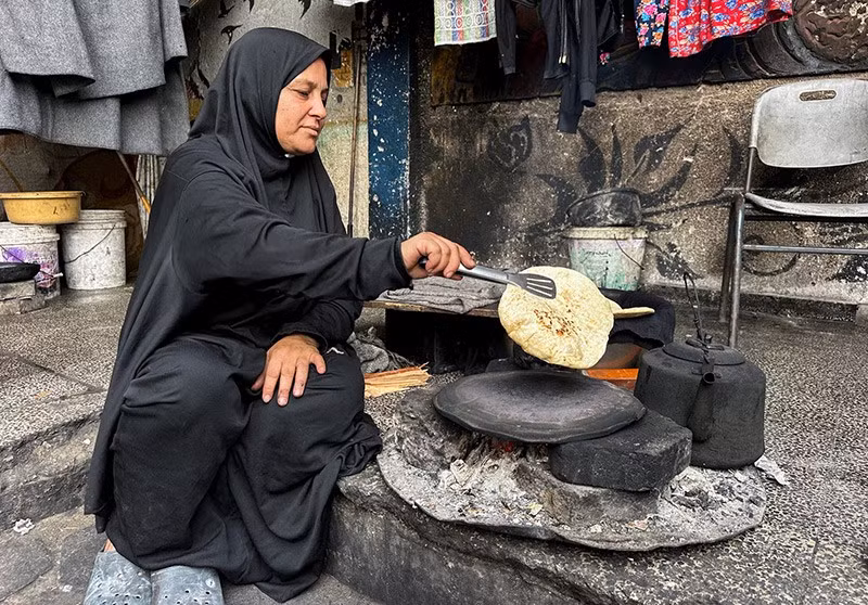 Một phụ nữ Palestine nướng bánh trên lửa giữa lệnh ngừng bắn tại Khan Younis, phía nam Dải Gaza. Ảnh: Reuters chum-anh-dai-gaza-khi-mua-dong-dang-den-gan-1105-019.jpg