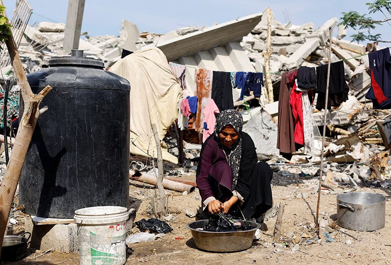 Một phụ nữ Palestine giặt quần áo trong chậu bên cạnh đống đổ nát giữa lệnh ngừng bắn tại Gaza City. Ảnh: Reuters chum-anh-dai-gaza-khi-mua-dong-dang-den-gan-1105-010.jpg