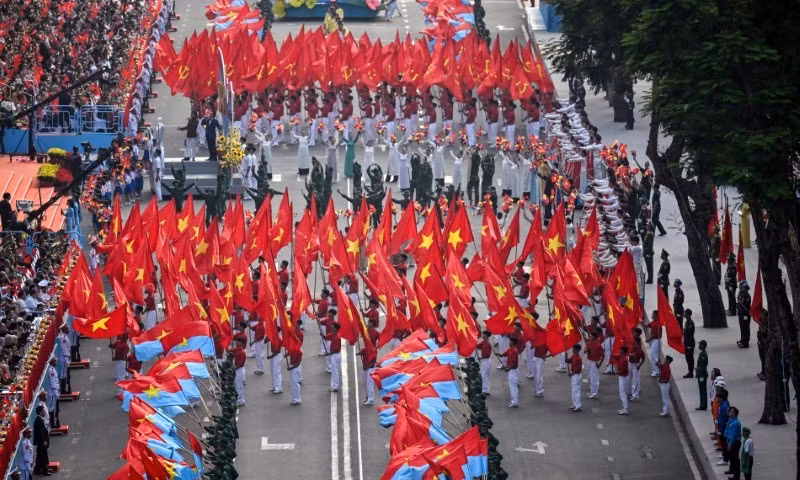 Người tham gia vẫy cờ trong lễ kỷ niệm 50 năm ngày thống nhất đất nước. Ảnh: AFP. hinh-anh-viet-nam-ky-niem-50-nam-ngay-thong-nhat-tren-bao-quoc-te-13.jpg