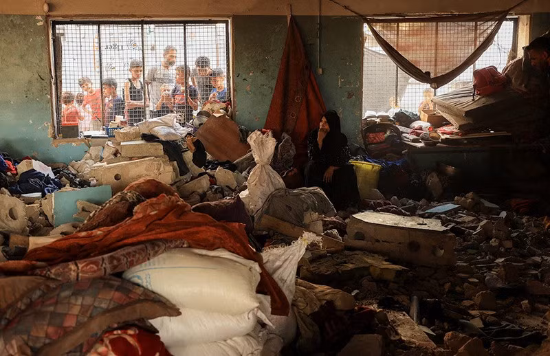 Một phụ nữ ngồi giữa đống đổ nát khi người Palestine kiểm tra hiện trường trường học trú ẩn người tị nạn bị không kích qua đêm, ở Gaza City, ngày 7/9. Ảnh: Reuters chum-anh-israel-doi-bom-thanh-pho-gaza-019.jpg