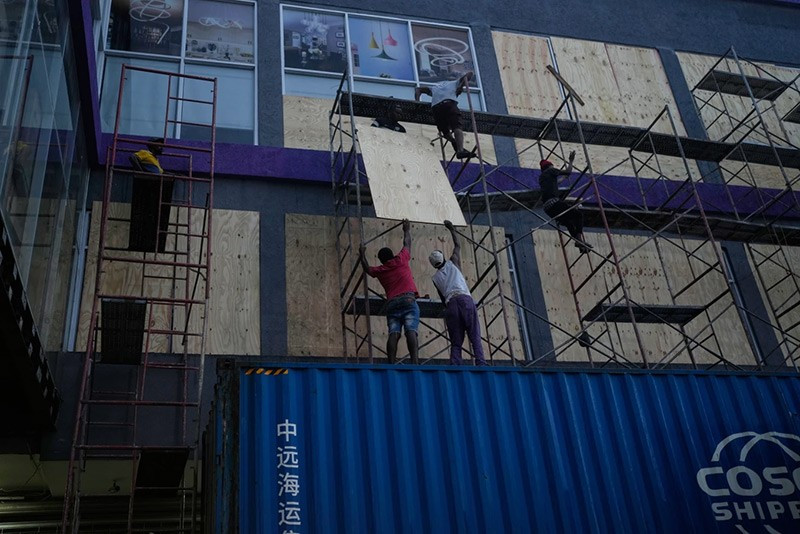 Công nhân đóng ván che cửa sổ các cửa hàng trước khi Bão Melissa đổ bộ vào Kingston, Jamaica. chum-anh-bao-melissa-anh-huong-vung-caribe-05-09.jpg