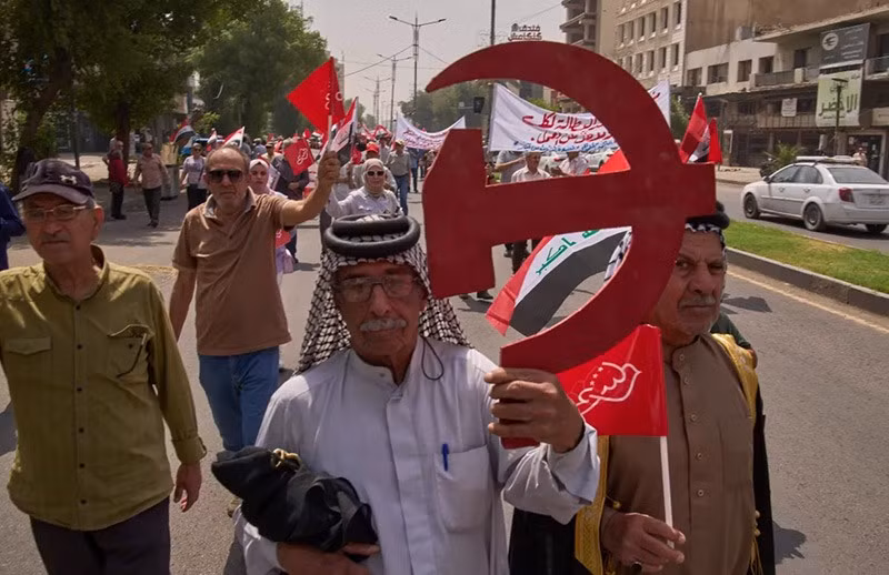 Một người ủng hộ Đảng Cộng sản Iraq vẫy biểu tượng búa liềm cùng cờ cộng sản và cờ Iraq khi họ tham gia lễ kỷ niệm Ngày Quốc tế Lao động tại Baghdad, Iraq. Ảnh: Hadi Mizban/AP. chum-anh-tuan-hanh-ngay-quoc-te-lao-dong-0505-06.jpg