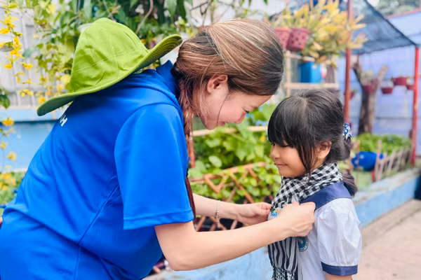 Du học sinh Việt Nam tại Úc trao khăn rằn tình nguyện cho học sinh xã Thạnh An. Ảnh: Thùy Linh.