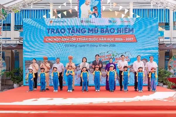 Các đại biểu trao tặng mũ bảo hiểm cho các em học sinh lớp Một trường Tiểu học Ngô Mây.