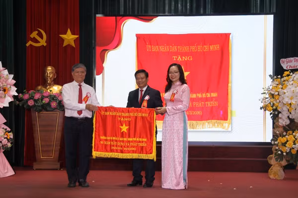 Ông Nguyễn Văn Hiếu - Giám đốc Sở GD&ĐT TPHCM trao cờ truyền thống của Uỷ ban Nhân dân TPHCM cho Trường Cán bộ Quản lý Giáo dục TPHCM. Ảnh: Thùy Linh. 