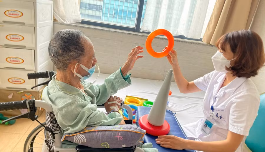 Chị Nguyễn Thị Cúc - cựu sinh viên Trường Đại học Kỹ thuật Y tế Hải Dương can thiệp hoạt động trị liệu cho người bệnh tại Bệnh viện Lão khoa Trung ương.