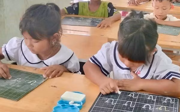 Học sinh người Cơ Ho nắn nót những nét chữ đầu tiên.