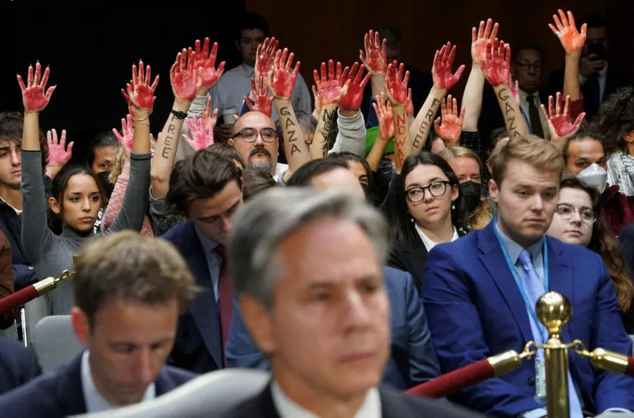 Những người biểu tình phản chiến với đôi bàn tay "đẫm máu" ngồi phía sau Bộ trưởng Ngoại giao Mỹ Antony Blinken trong phiên điều trần của Ủy ban Tài chính Thượng viện về yêu cầu cấp thêm 106 tỷ USD cho an ninh quốc gia bao gồm hỗ trợ Israel và Ukraine, tăng cường an ninh biên giới, ngày 31 tháng 10 năm 2023. 
